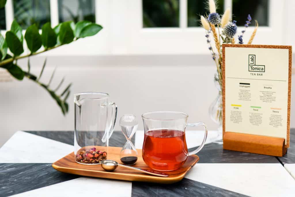 Cup of Lab Tonica herbal tea with a tea timer and tea menu